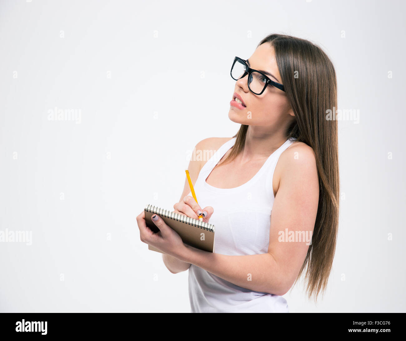 Portrait of a cute female student making notes in notepad and looking ...