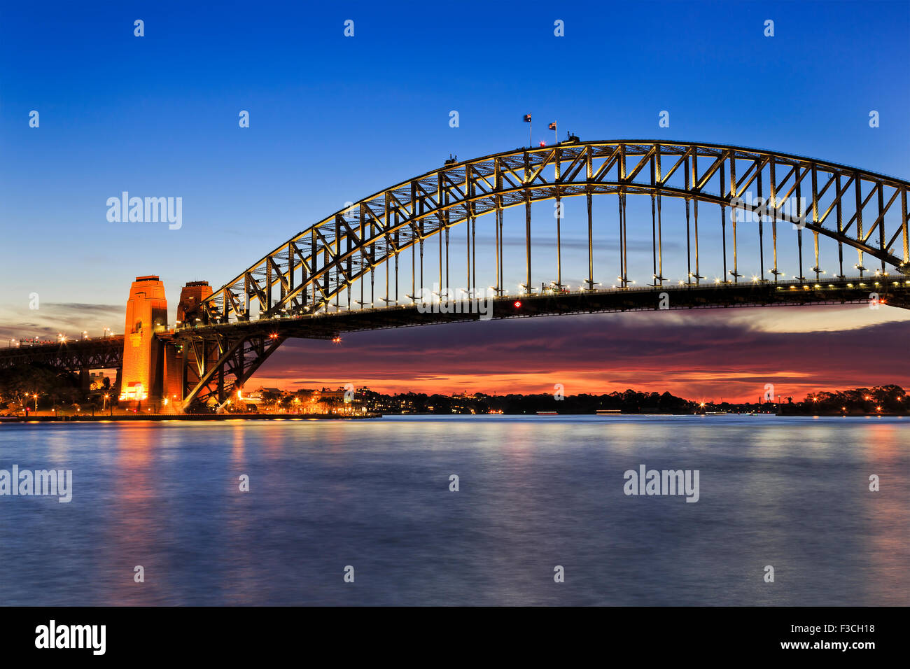 Side view of Sydney Harbour bridge at sunrise with scarlett sun light and illumination of still arch Stock Photo