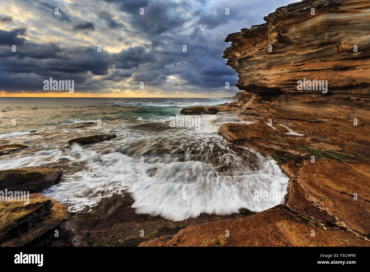 rugged coast of Australia nea Sydney at sunrise. Stormy wavers eroding sandstone rocks. Stock Photo