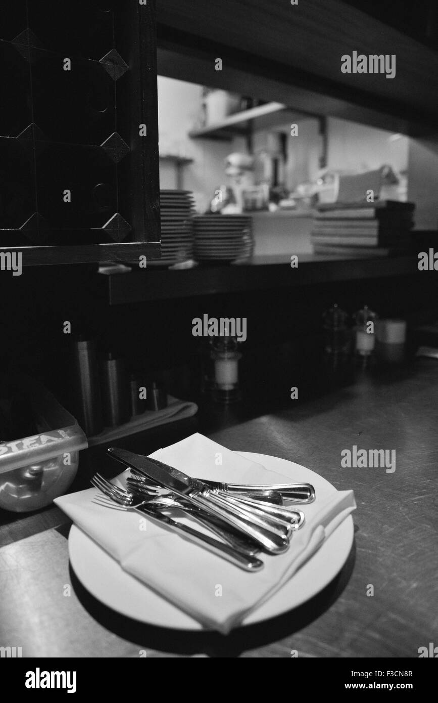 Plates, napkins, and utensils stacked on table Stock Photo