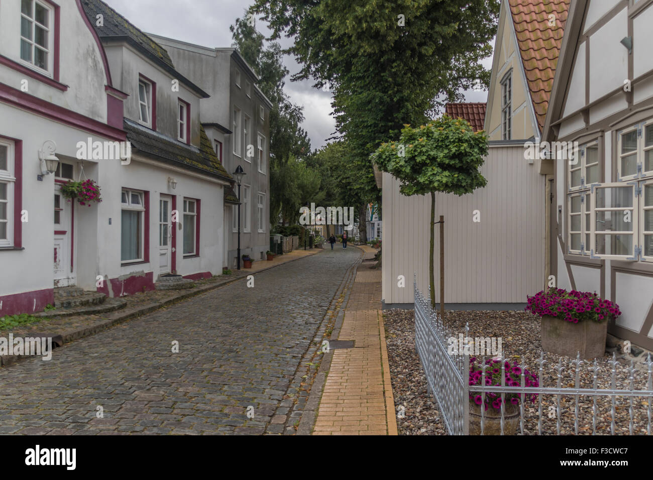 Two people walking along a quaint cobblestoned street in the German Baltic seaside resort town of Warnemunde Stock Photo