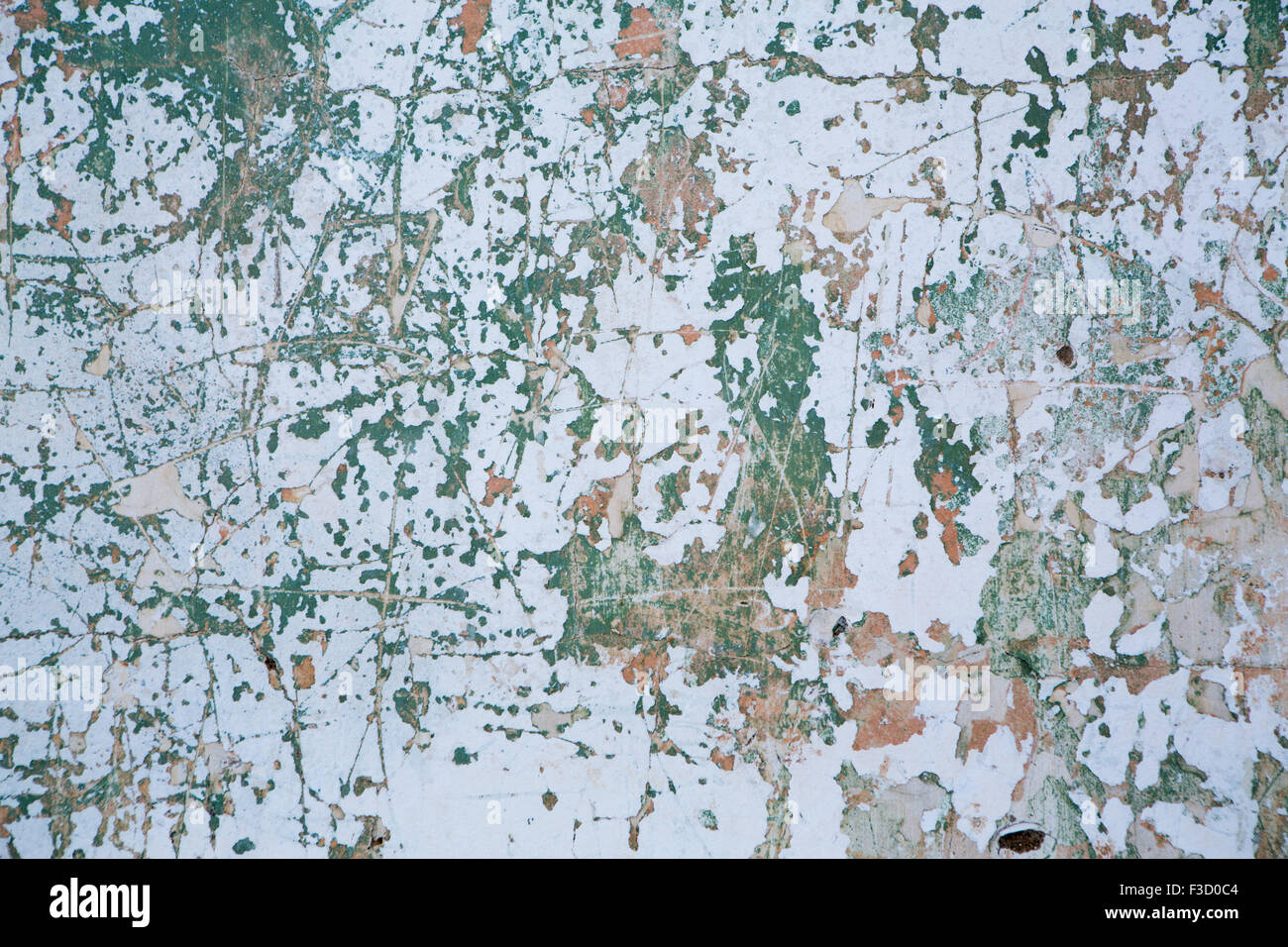 Grunge wall texture background.  Paint cracking off dark wall with rust underneath. Stock Photo