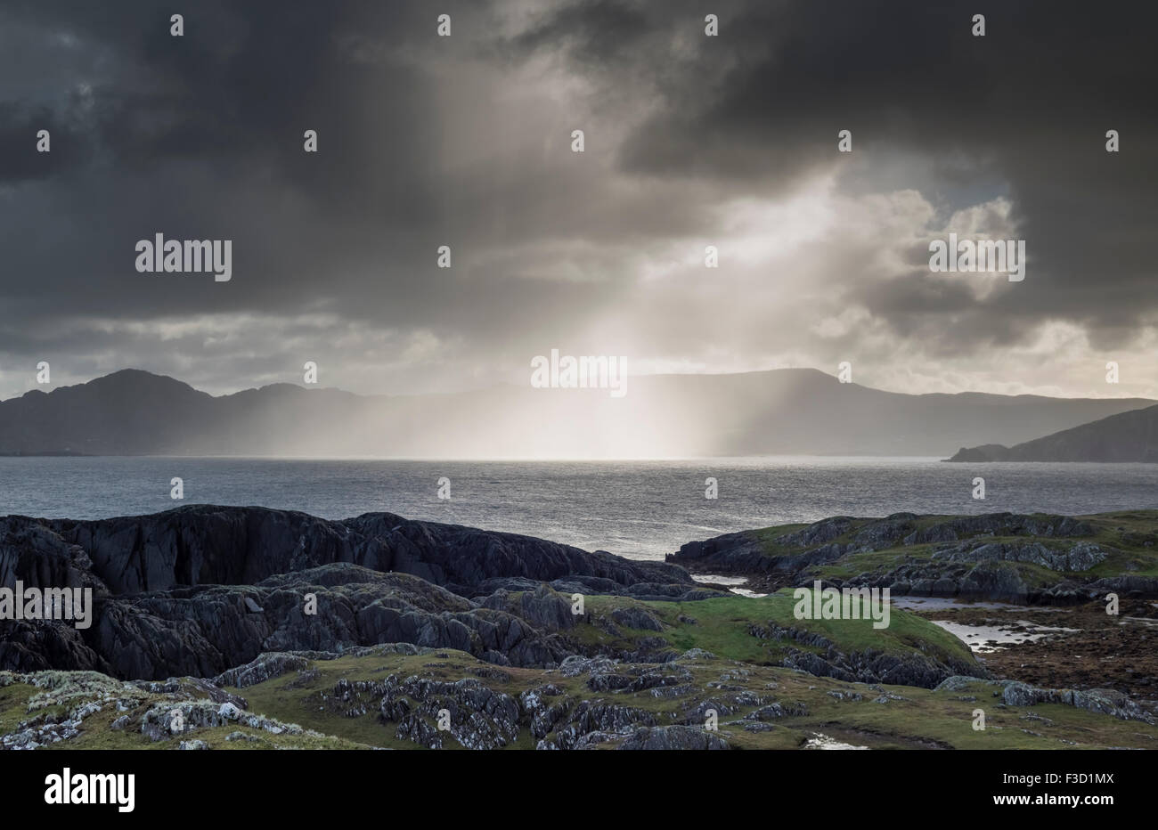 Rain shower and sunburst over Ballydonegan Bay from Garinish looking towards Allihies, Beara Peninsula, County Cork, Ireland Stock Photo