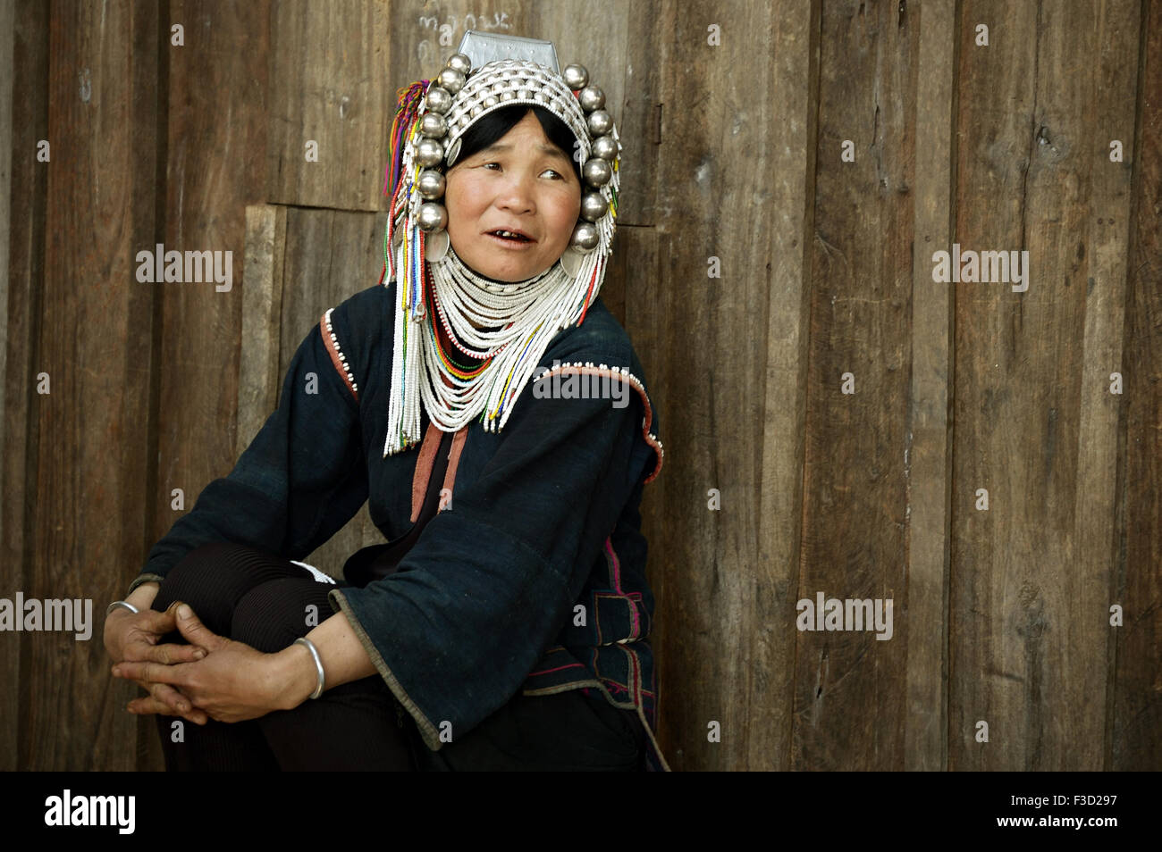 Akha woman sitting outside her wooden house in a village around Kengtung (Kyaingtong), Shan State, Myanmar Stock Photo