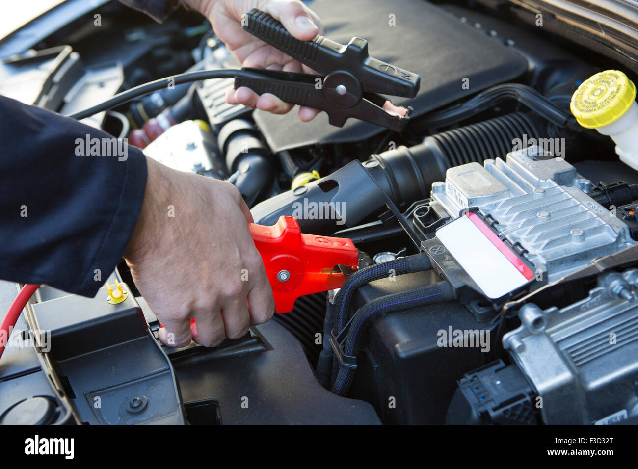 Close-Up Of Mechanic Attaching Jumper Cables To Car Battery Stock Photo
