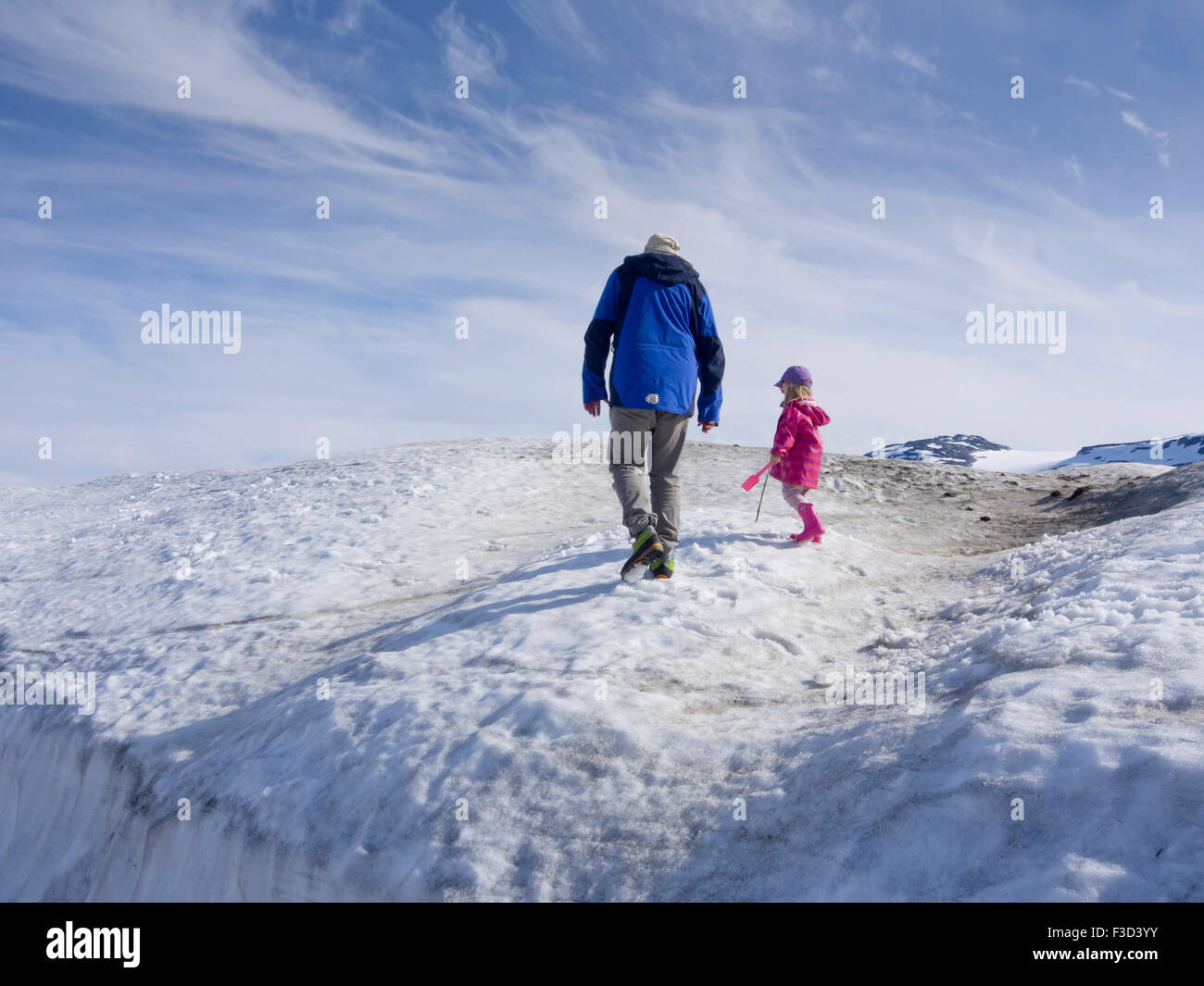 Grandfather and young girl with spade on a heap of snow, sunny summer, Norwegian mountains Finse, Hardangervidda Norway Stock Photo