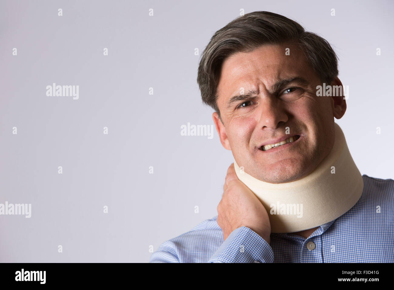 Studio Shot Of Man In Pain Wearing Neck Brace Stock Photo