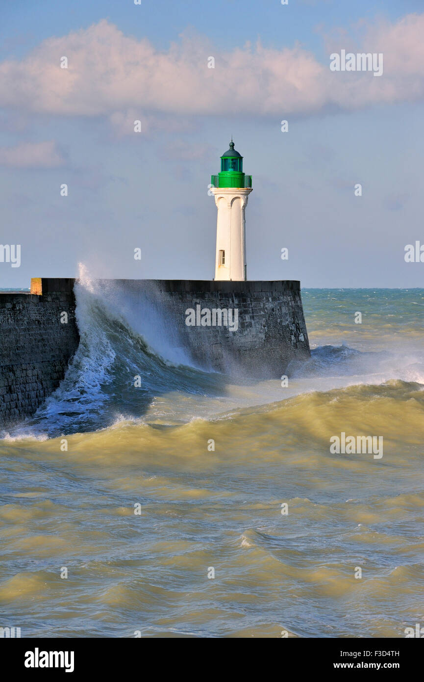 Wave crashing into mole with lighthouse during rough sea at Saint-Valéry-en-Caux, Normandy, France Stock Photo