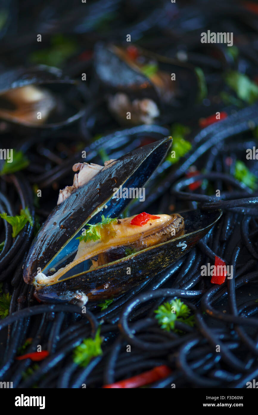 Squid ink Spaghetti with Mussels, garlic , chilli and parsley. Stock Photo