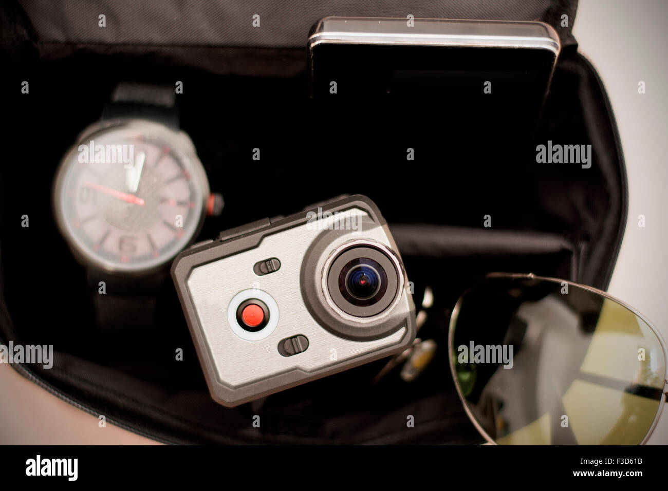 Wristwatch, sunglasses, smart phone and very small action camera in little black men bag. Male accessories. Stock Photo