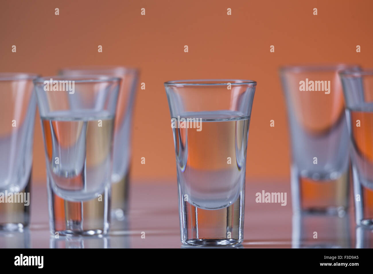 shot glass filled with vodka on a orange background Stock Photo - Alamy