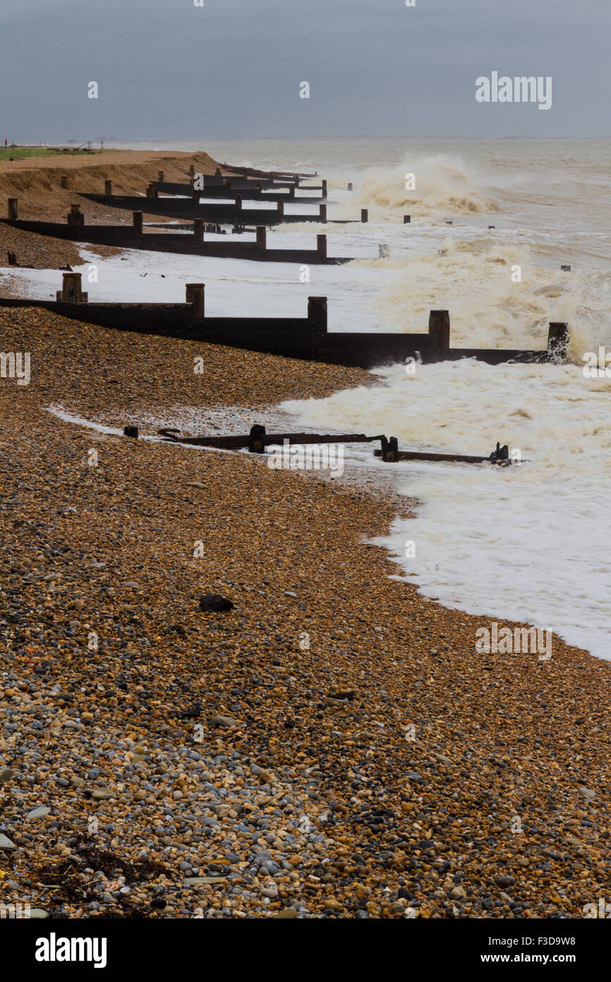 Stormy stony beach, waves crashing with Groynes groins. Winchelsea Beach, Winchelsea Beach, Hastings, Kent, England, United King Stock Photo
