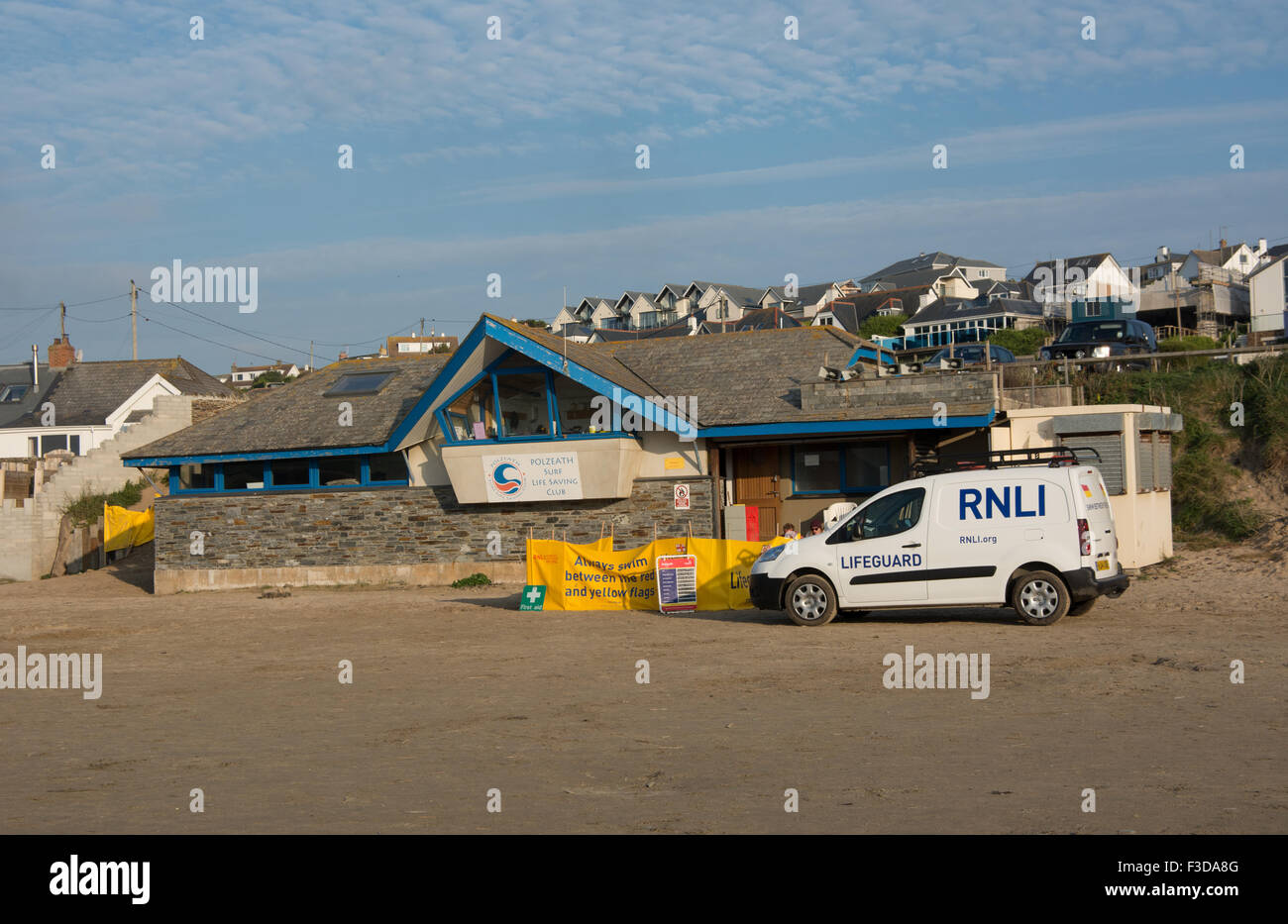 A RNLI Lifeguards van is parked outside the Polzeath Surf Life Savers club building at the end of  a sunny day Stock Photo