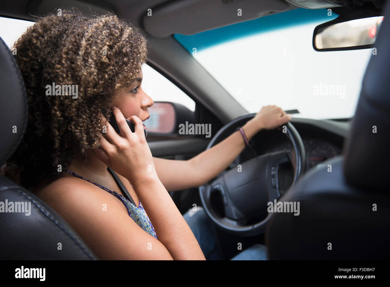 Young woman using phone while driving car Stock Photo