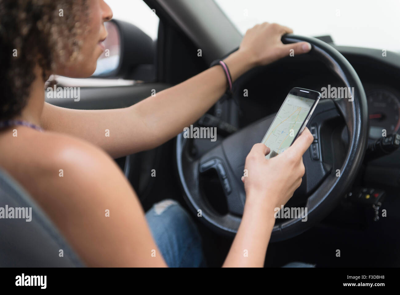 Young woman texting while driving car Stock Photo