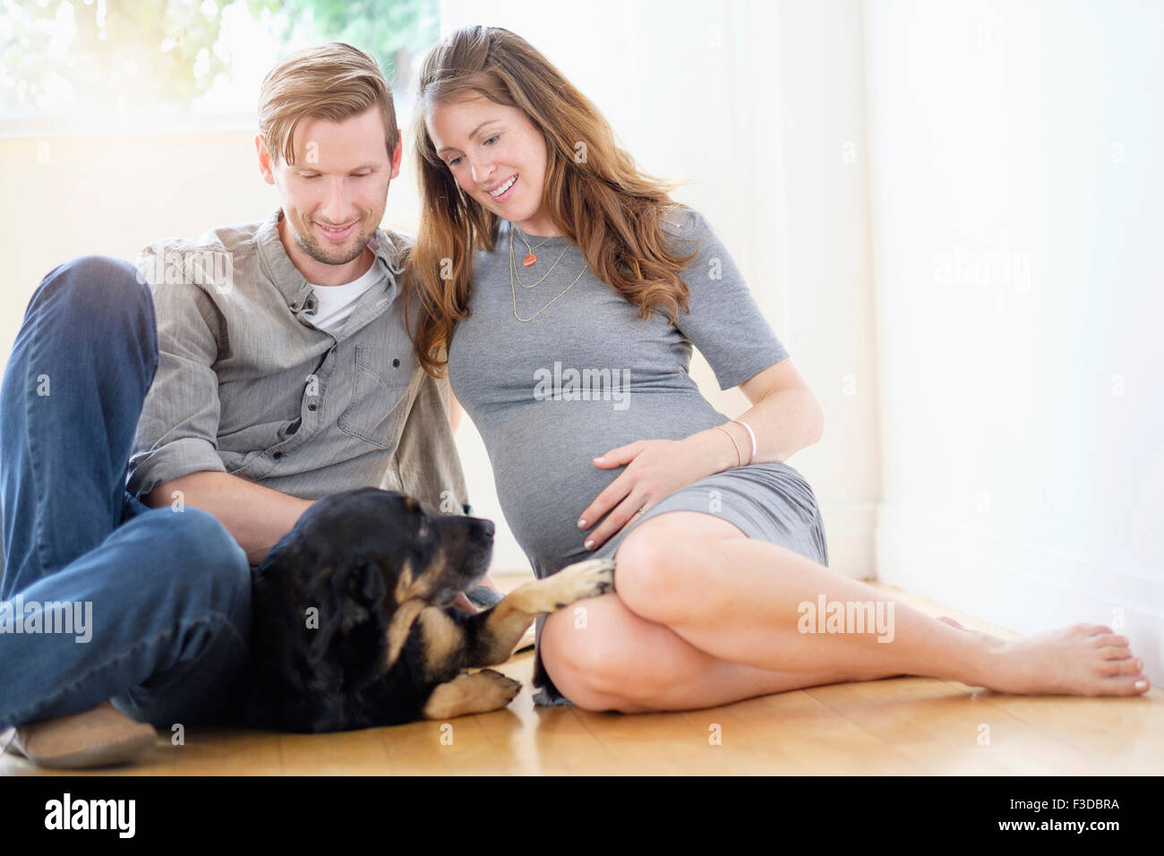 Couple relaxing with dog on floor Stock Photo