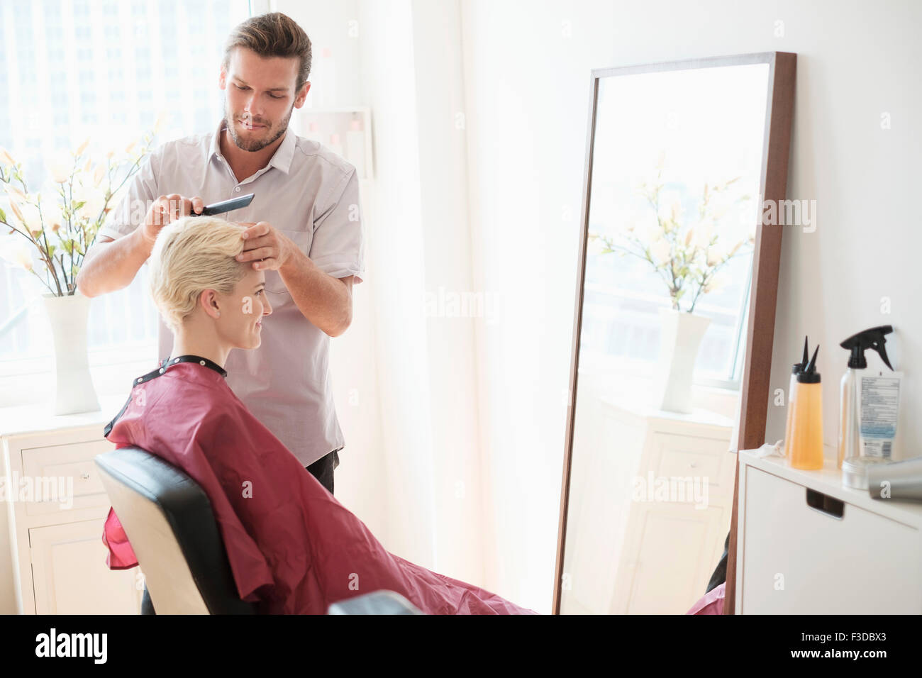 Hairdresser combing woman's hair Stock Photo