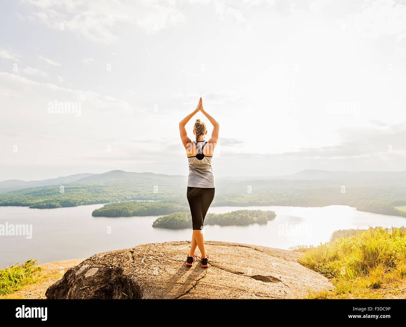 Rear view of young woman practicing yoga in front of lake Stock Photo ...