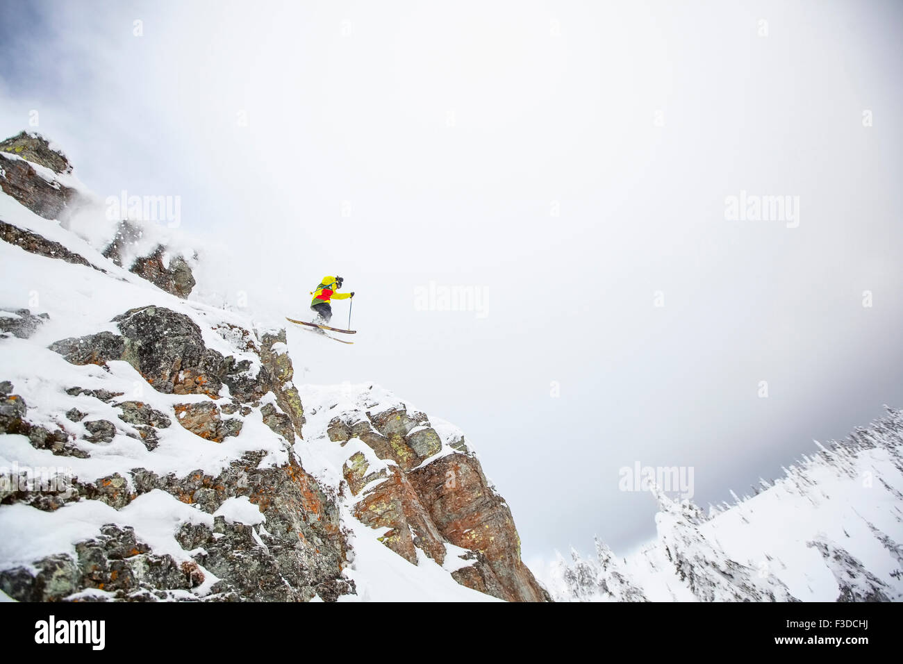 Skier jumping off rocky mountain Stock Photo