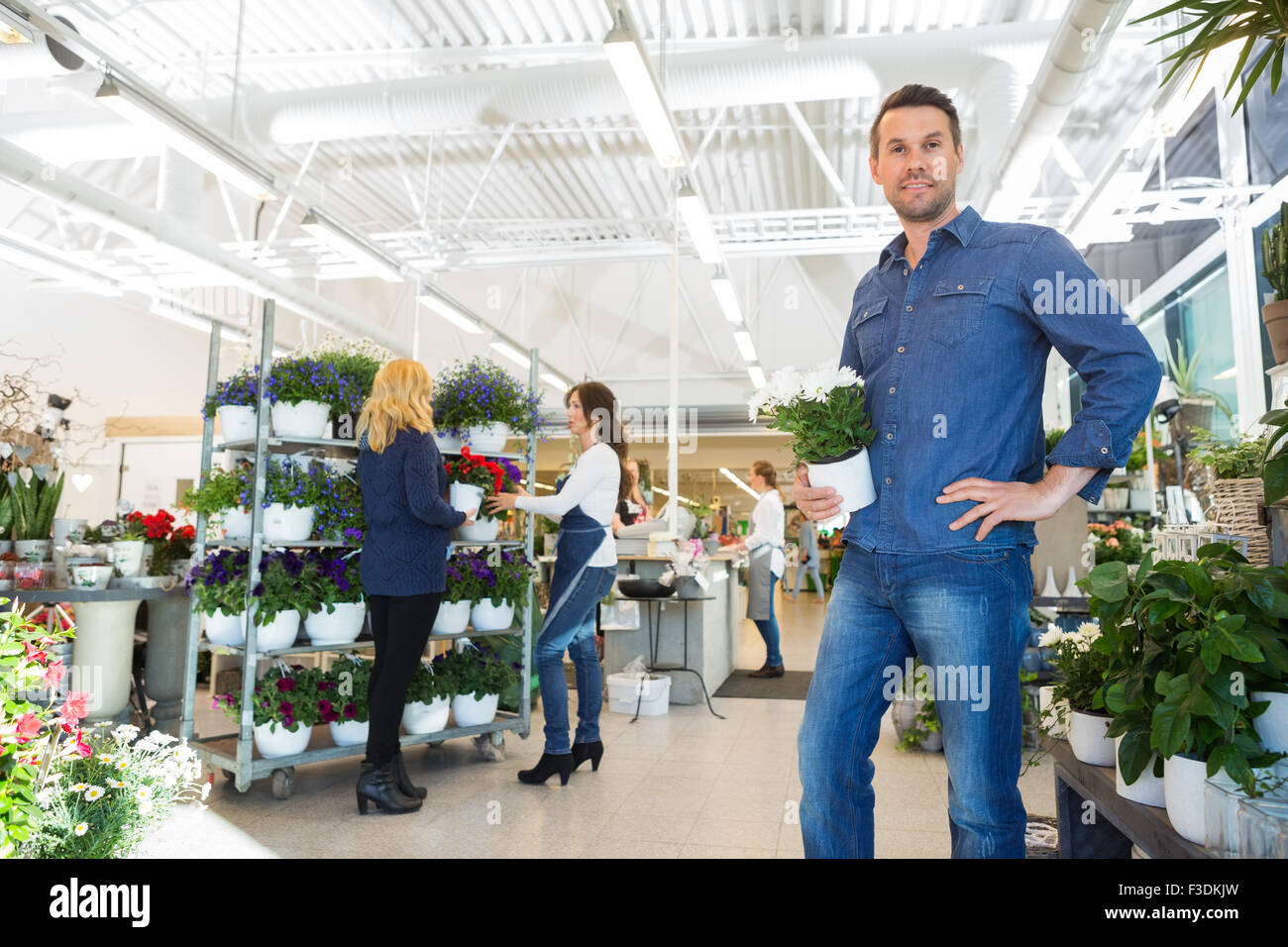 Portrait Of Man Holding Pot Plant In Flower Shop Stock Photo - Alamy