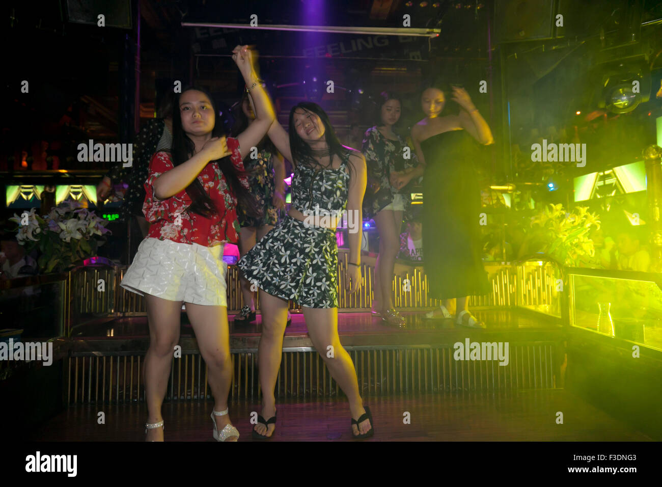 Revellers dancing to techno or electronic music on an elevated stage at a typical modern club in China. Stock Photo