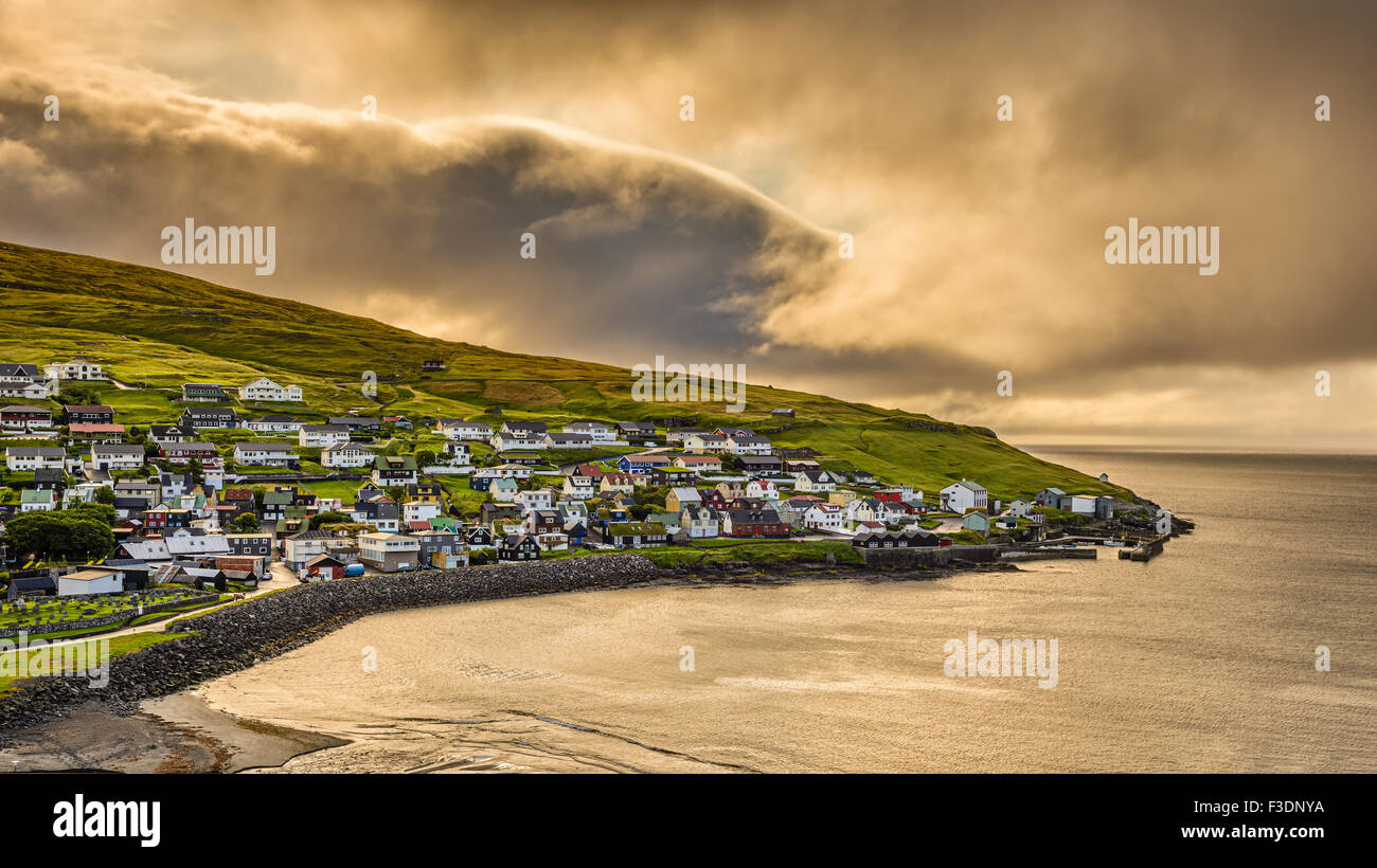 Sunrise above the village of Sandavagur with heavy clouds, Faroe Islands, Denmark. Hdr processed. Stock Photo
