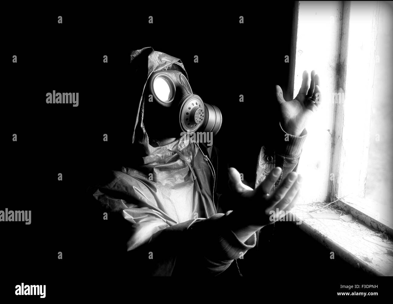 Person with gas mask looking into the bright light, creative image, worshiping the Midnight Sun of a nuclear strike Stock Photo