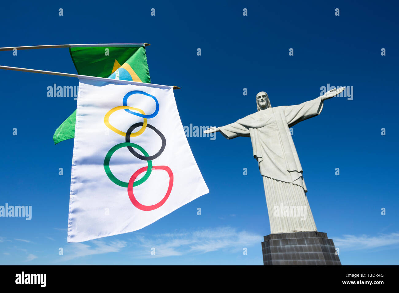 RIO DE JANEIRO, BRAZIL - MARCH 05, 2015: Olympic and Brazilian flags hang next to statue of Christ the Redeemer at Corcovado. Stock Photo
