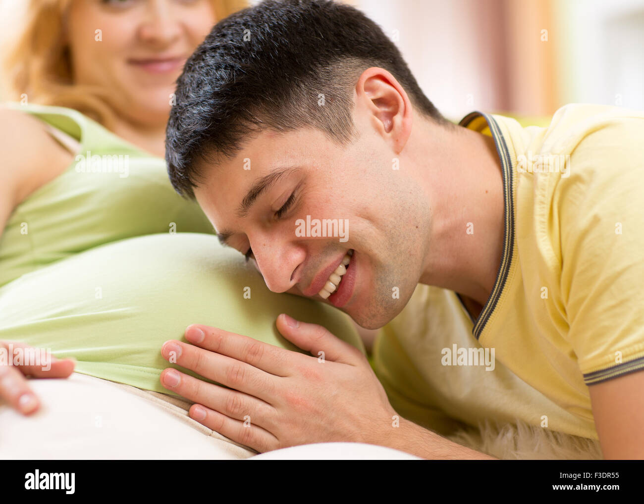 Young man strokes tummy of his pregnant woman. Careful husband with his pregnant wife. Stock Photo