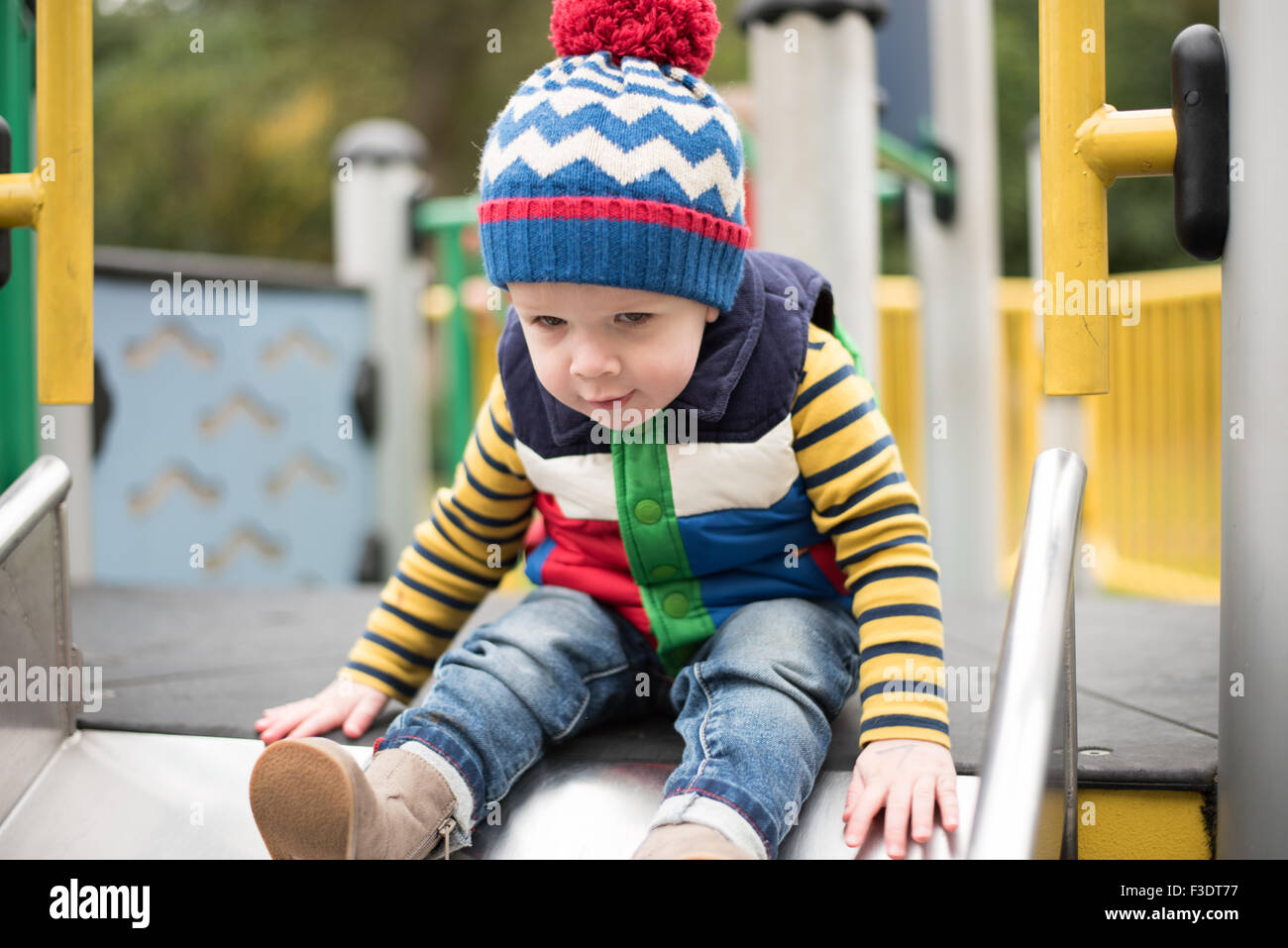 Young Boy playing in park on slide Stock Photo