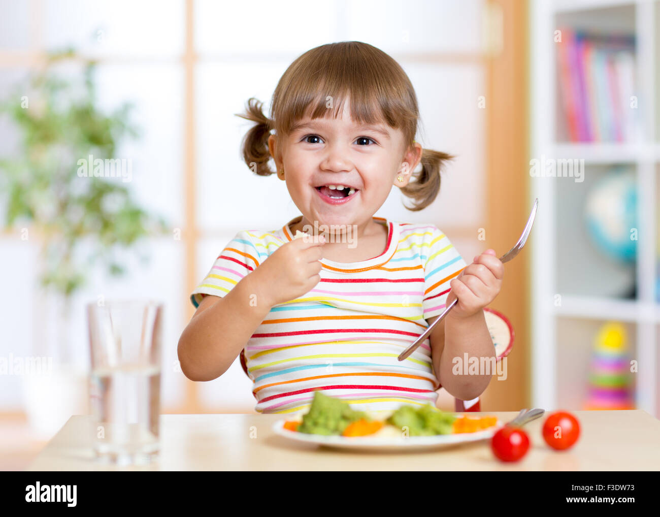 kid girl eating healthy vegetables Stock Photo
