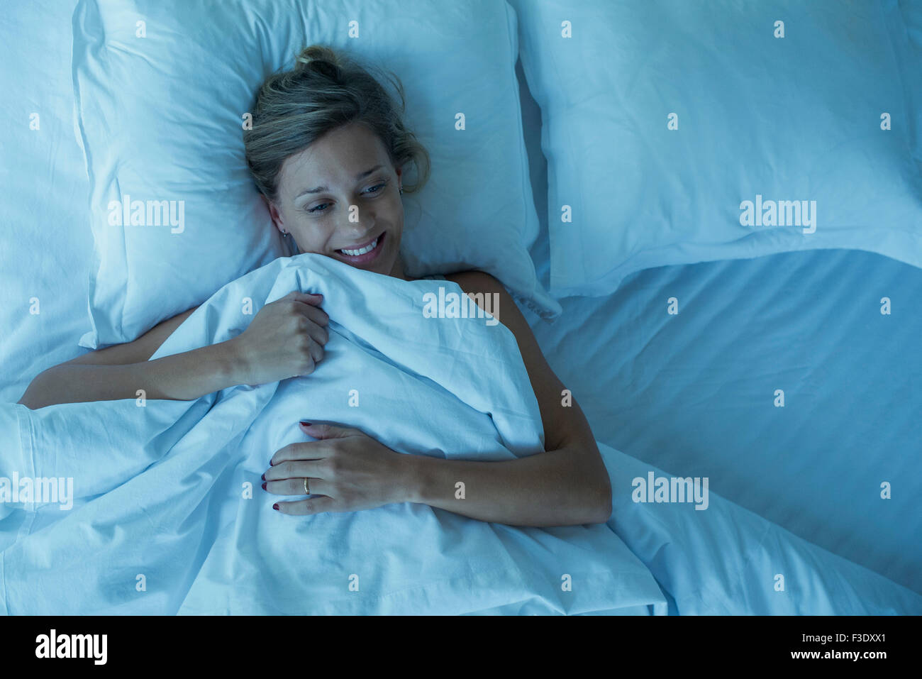 Woman lying in bed, smiling Stock Photo