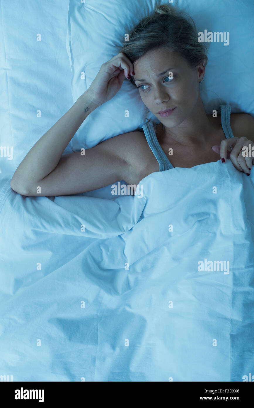 Woman lying awake in bed Stock Photo