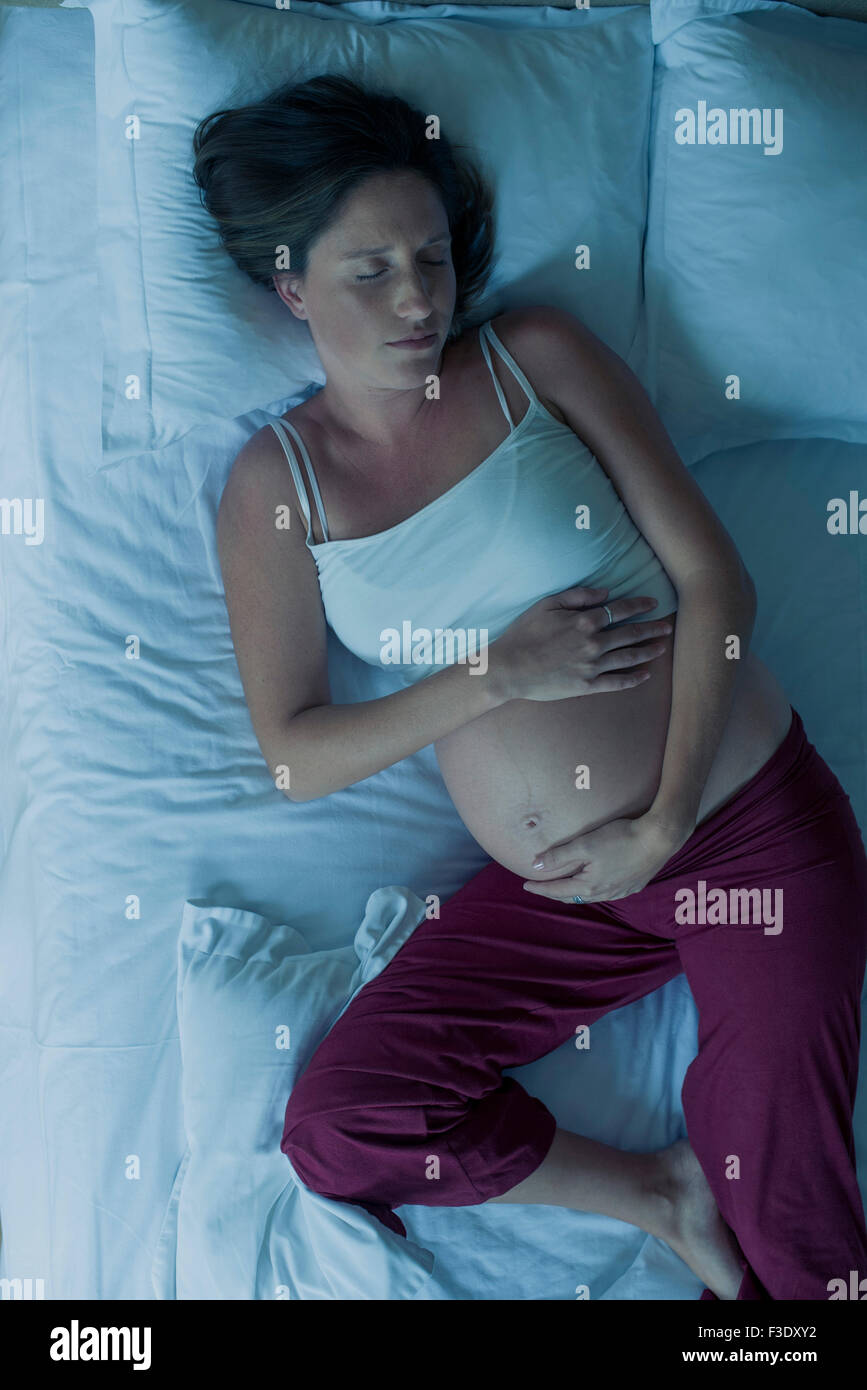 Pregnant woman sleeping on bed Stock Photo Alamy