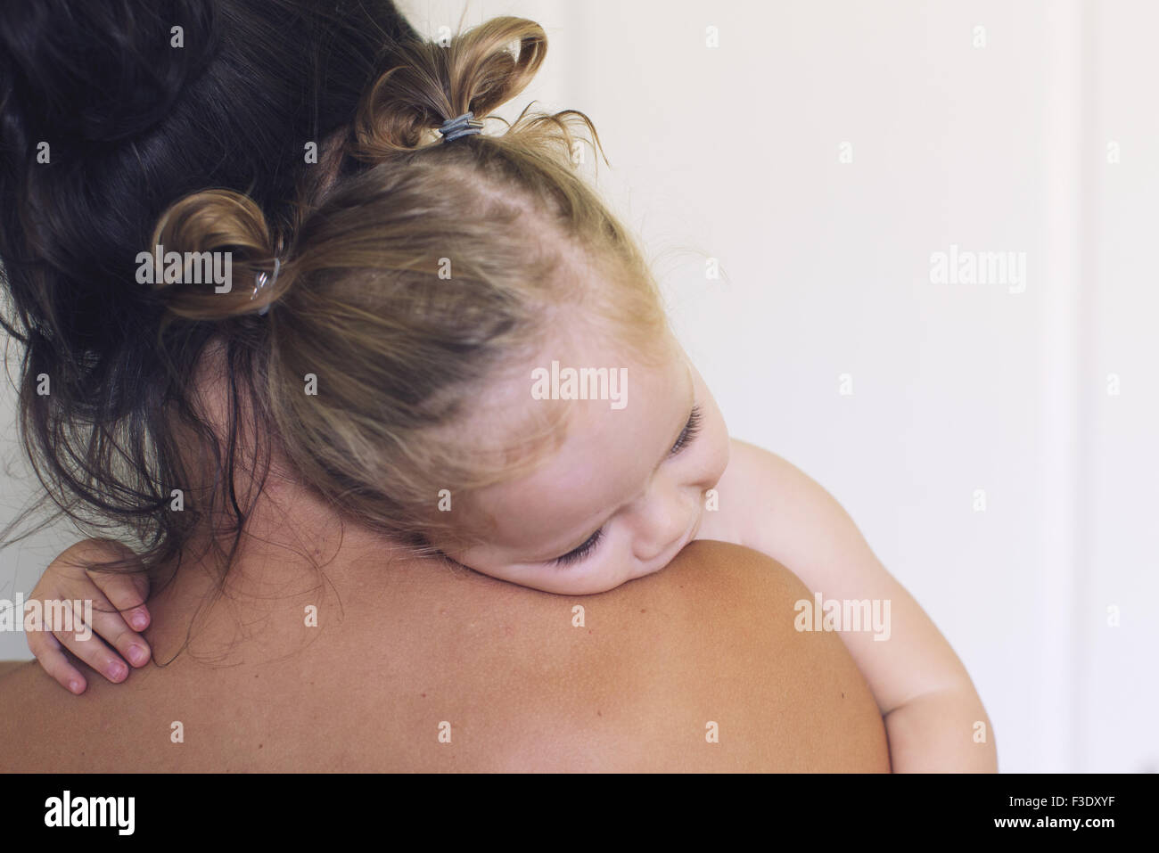 Baby girl resting her head on mother's shoulder Stock Photo