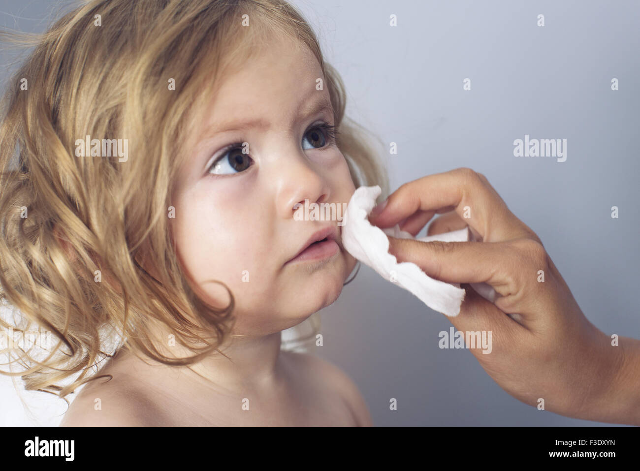 Parent wiping baby girl's face, cropped Stock Photo