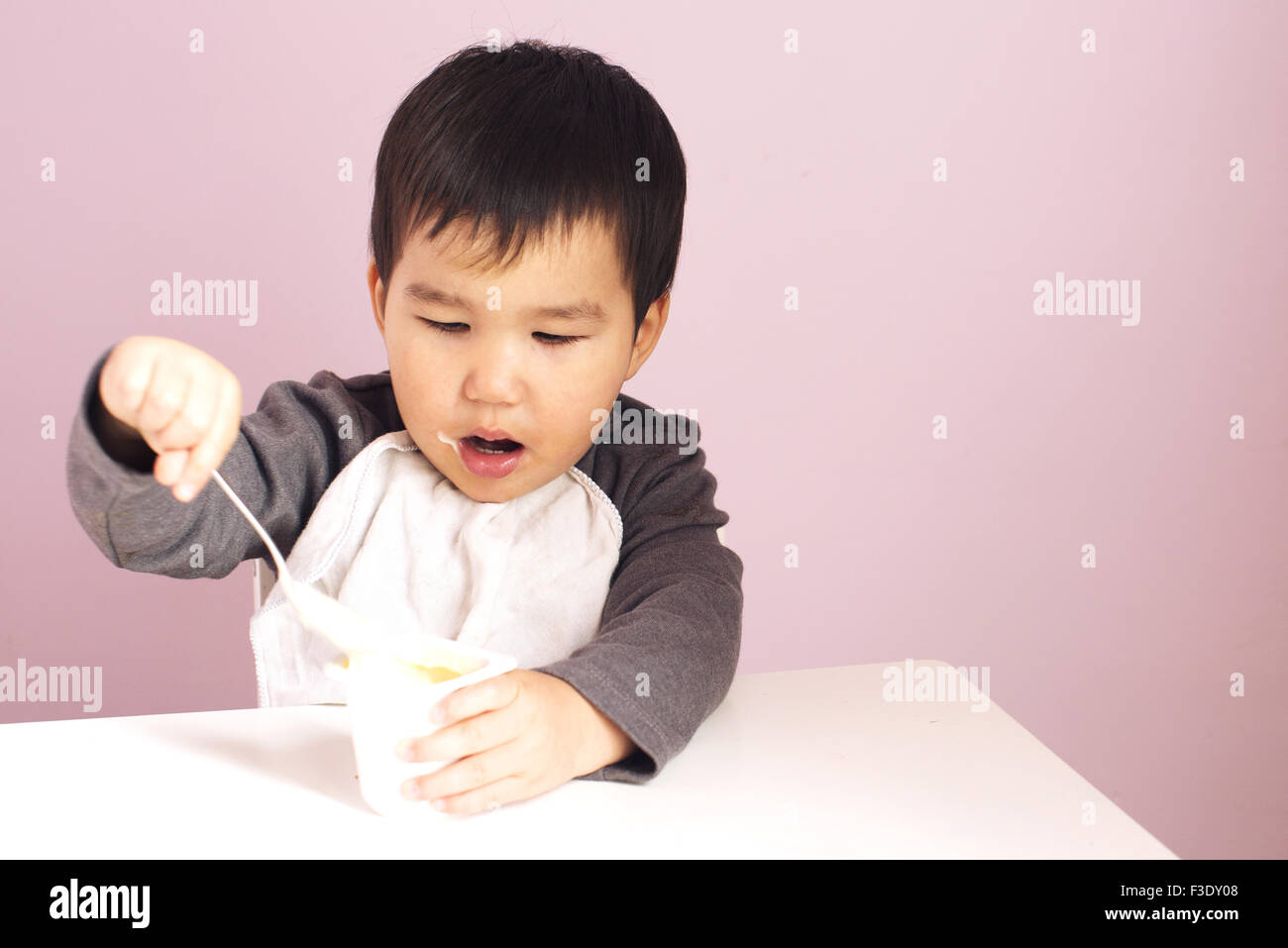 Baby feeding himself with a spoon Stock Photo