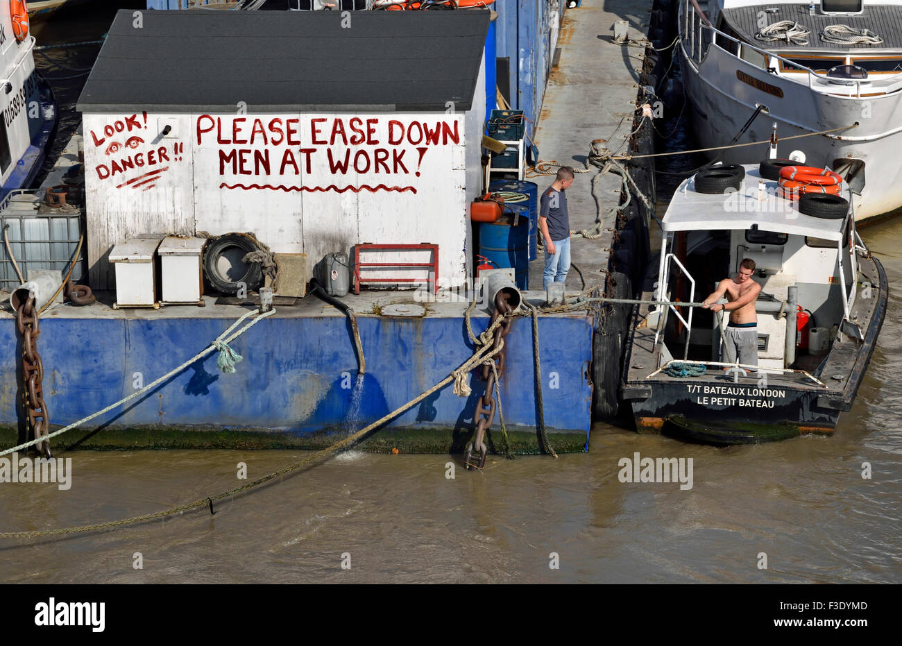 London, England, UK. Notice on a barge in the River Thames - Please Ease Down - Men at Work Stock Photo