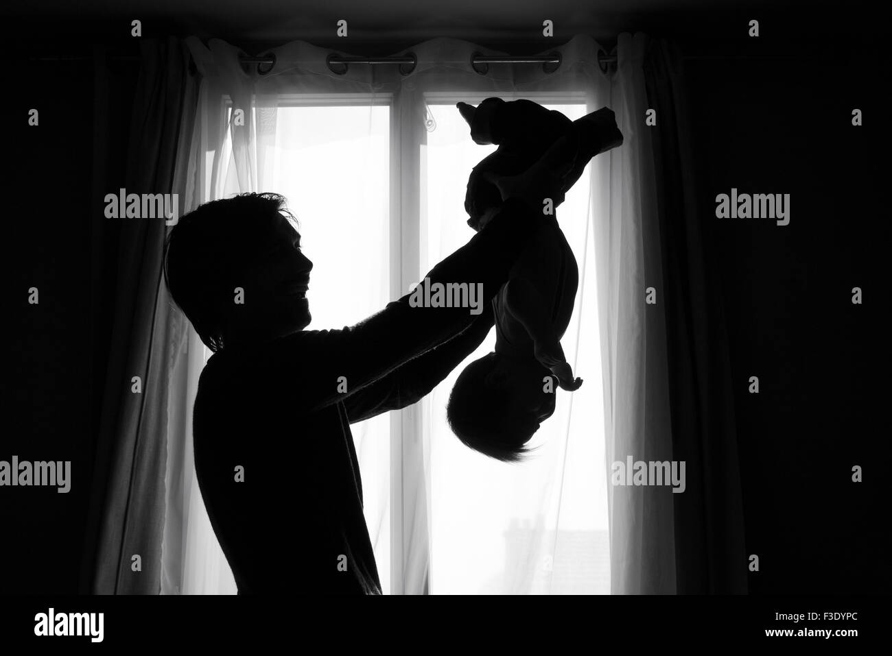 Father holding baby upside down Black and White Stock Photos & Images