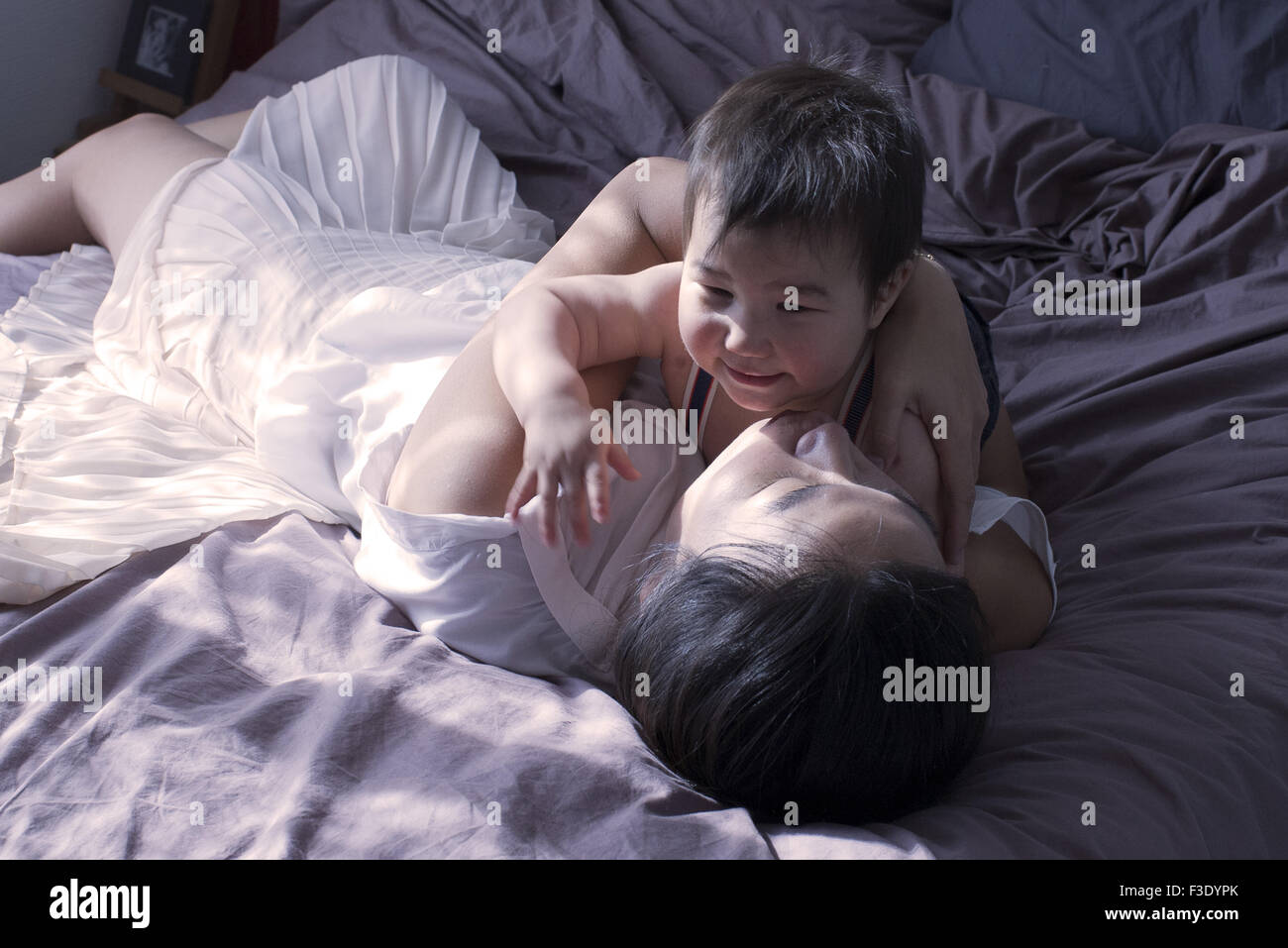 Mother and baby boy relaxing on bed together Stock Photo