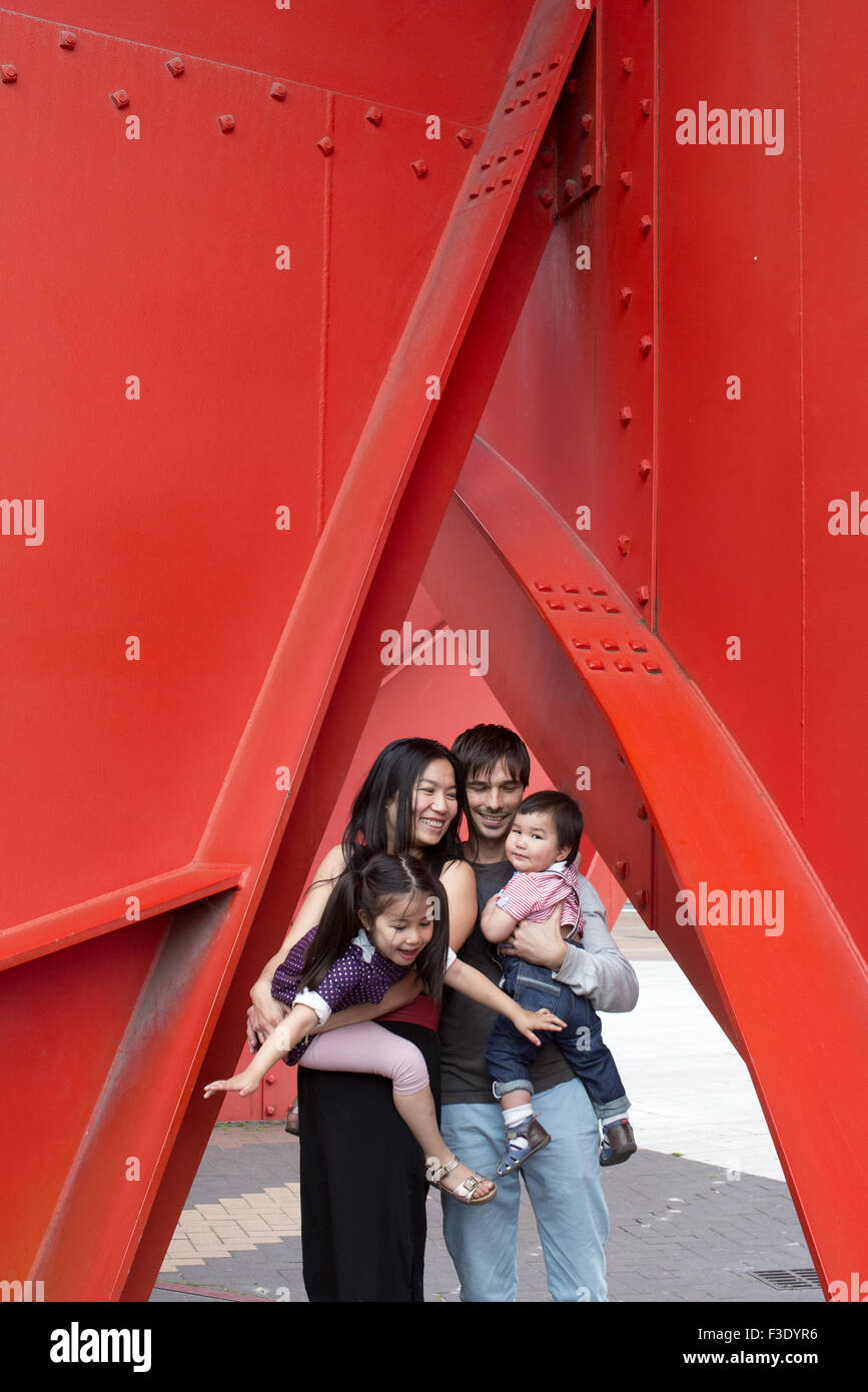 Family with two children standing beneath sculpture Stock Photo