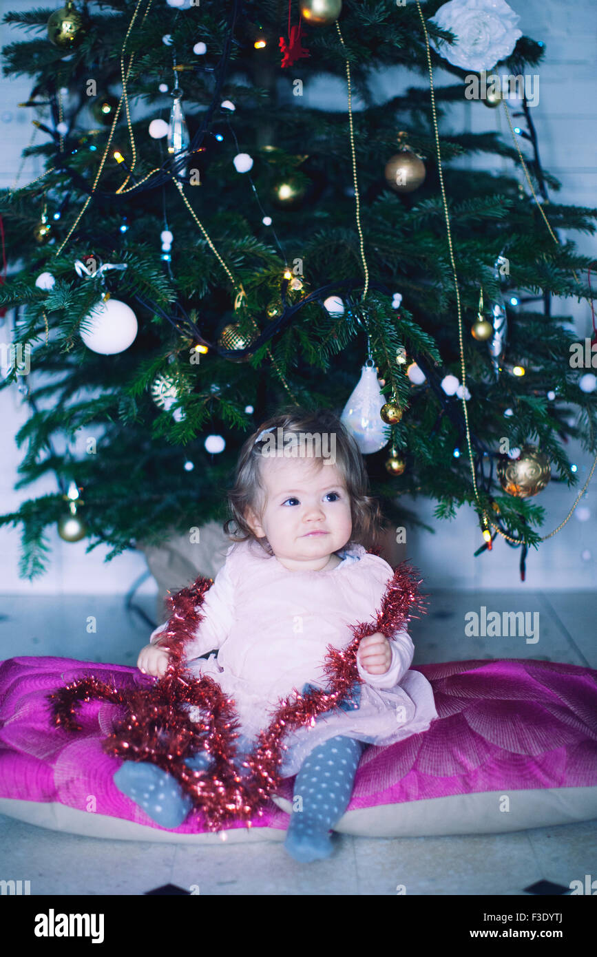 Baby girl sitting in front of Christmas tree, portrait Stock Photo