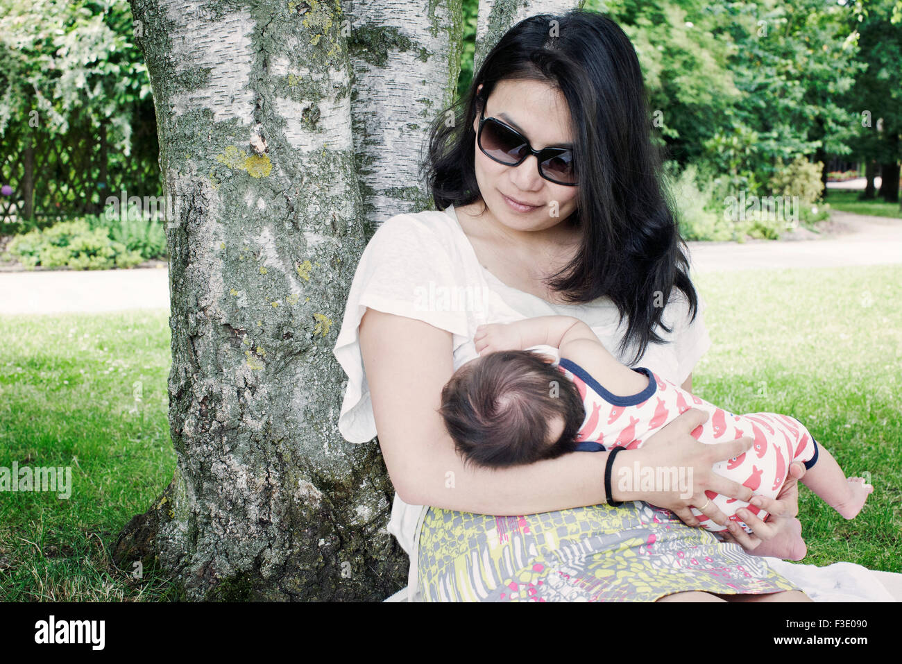 Woman breast feeding infant in park Stock Photo