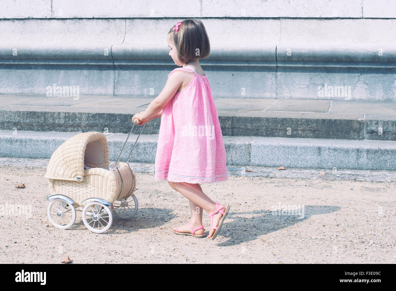 Little girl pushing toy baby carriage Stock Photo