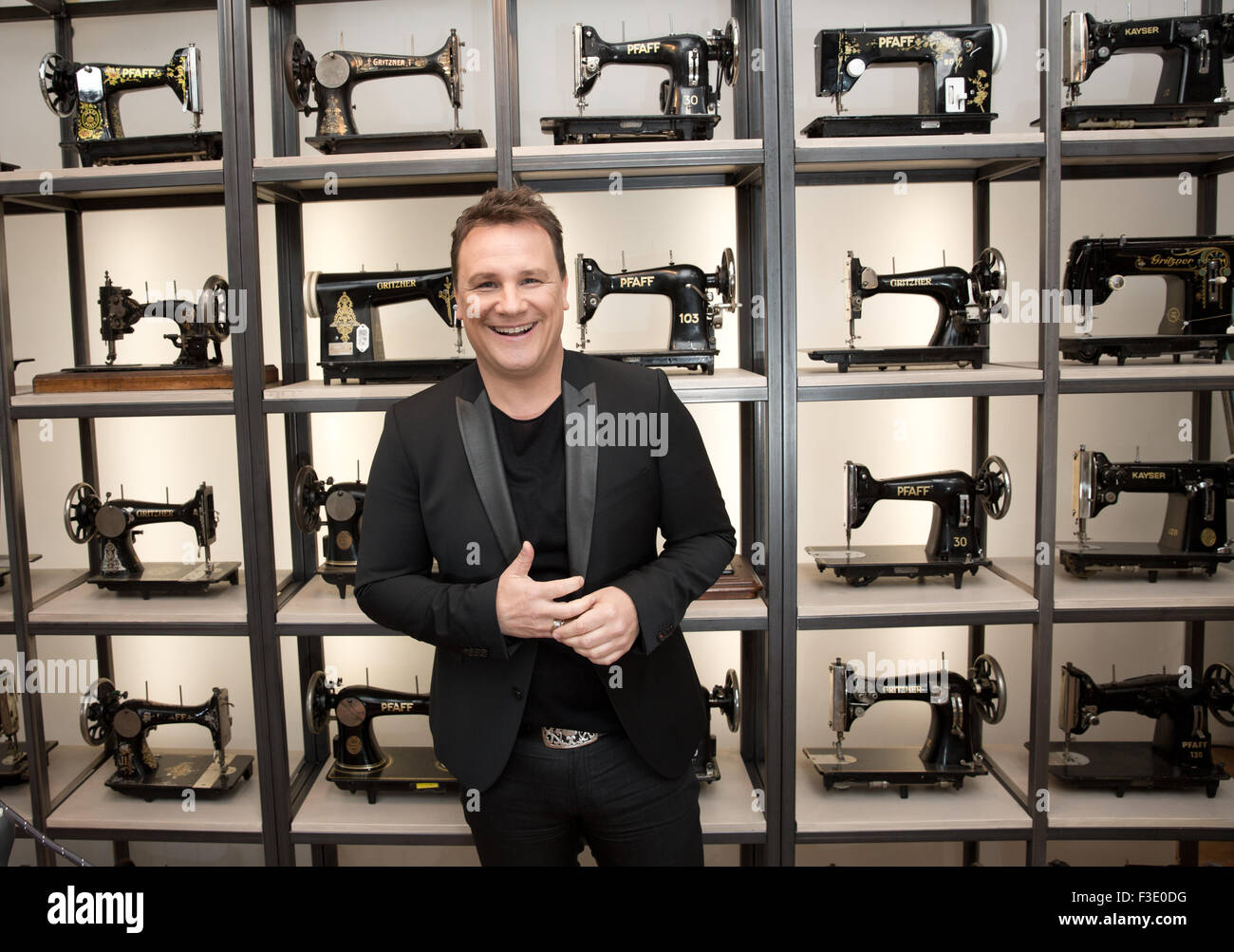 Fashion designer Guido Maria Kretschmer poses in front of shelves with antique sewing machine during filming for the VOX channel sewing competition 'Geschickt eingefaedelt - Wer naeht am besten?' (lit. Skilfully threaded - who sews the best?) in Berlin, Germany, 23 April 2015. Photo: JOERG CARSTENSEN/dpa Stock Photo