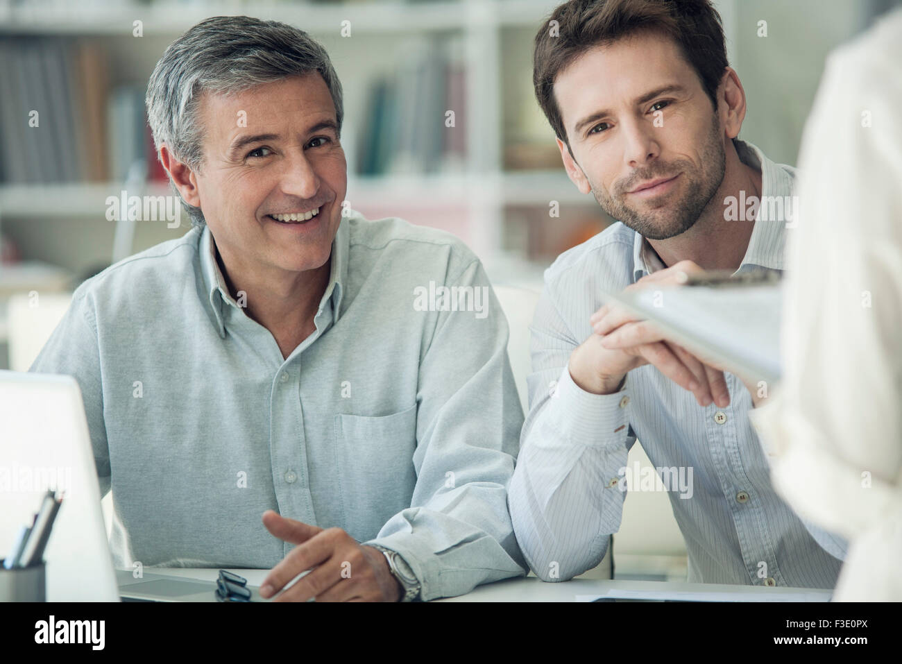 Businessmen sitting side by side, both smiling Stock Photo - Alamy