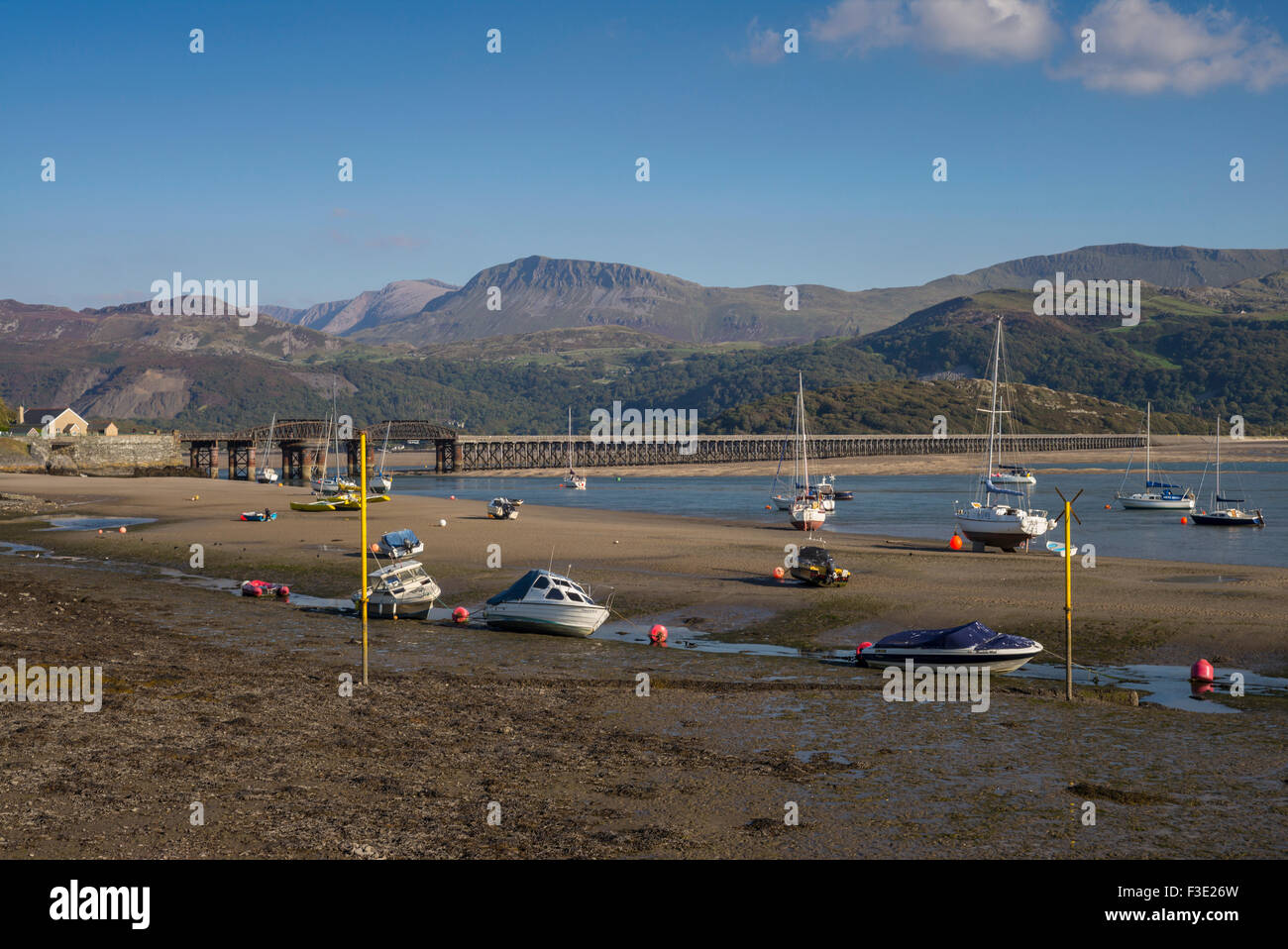 Late afternoon sun lights up a view of Barmouth harbour with old rail bridge and  Cader Idris mountain ranges in the distance. Stock Photo