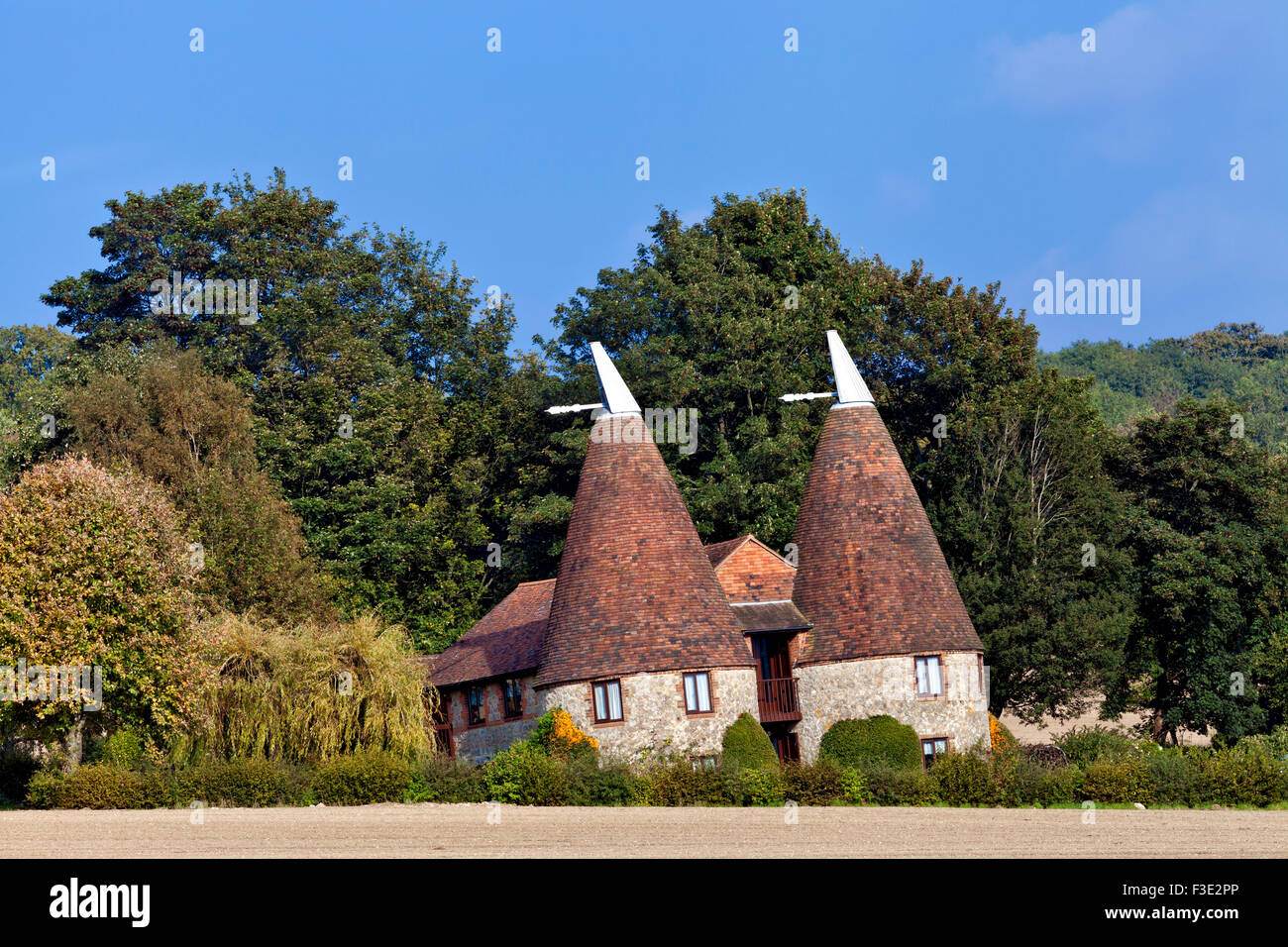Old traditional Kentish round stone oast house with white tipped cowls