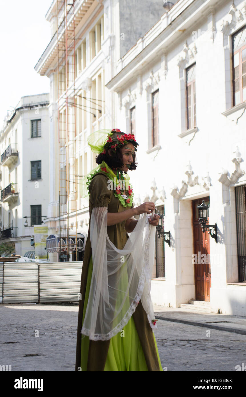 Costumed street performer with face makeup and green dress, standing on stilts in the old town of Havana on the island of Cuba Stock Photo