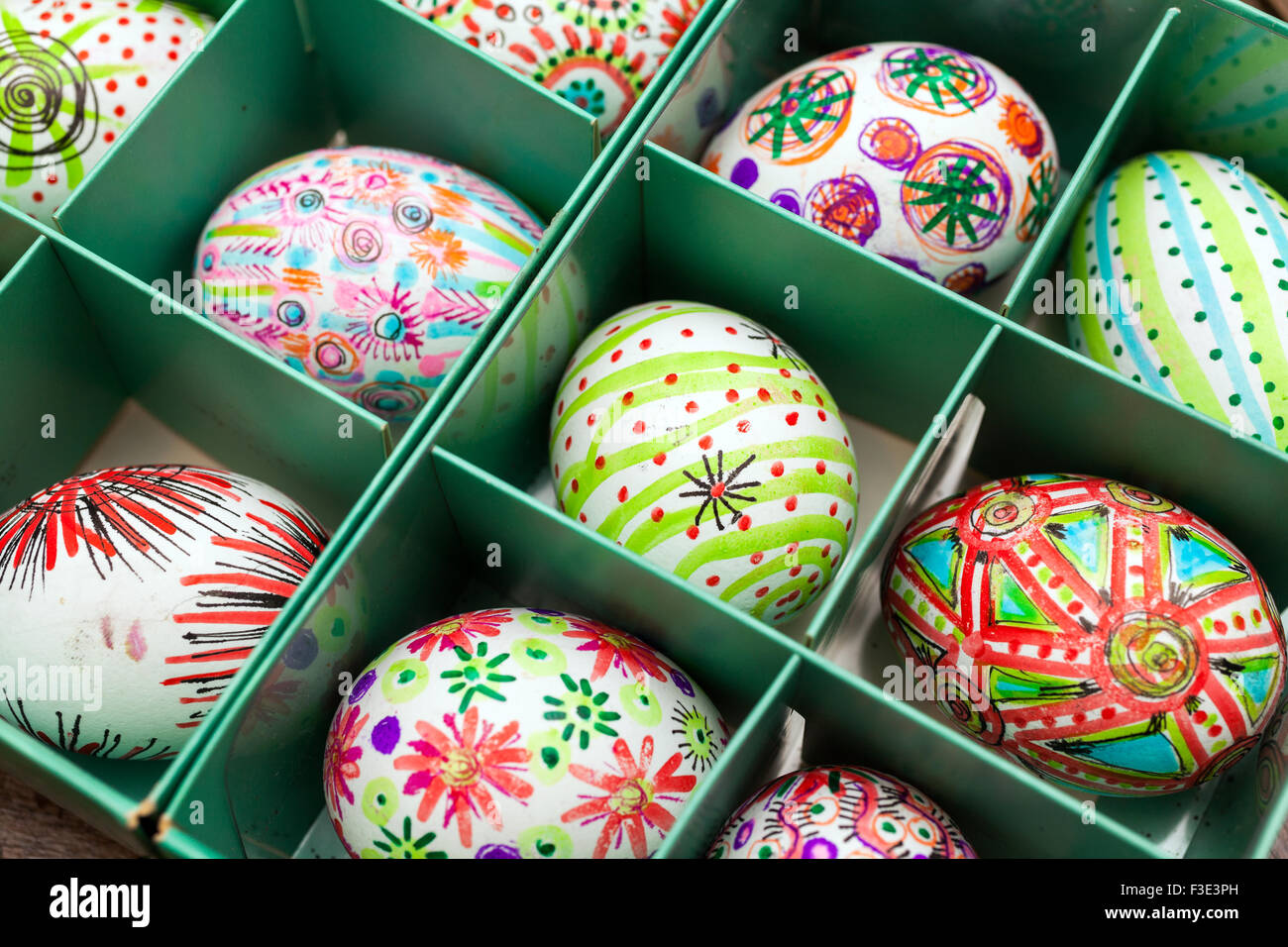 Hand painted colorful Easter eggs in green box on rustic wooden planks Stock Photo